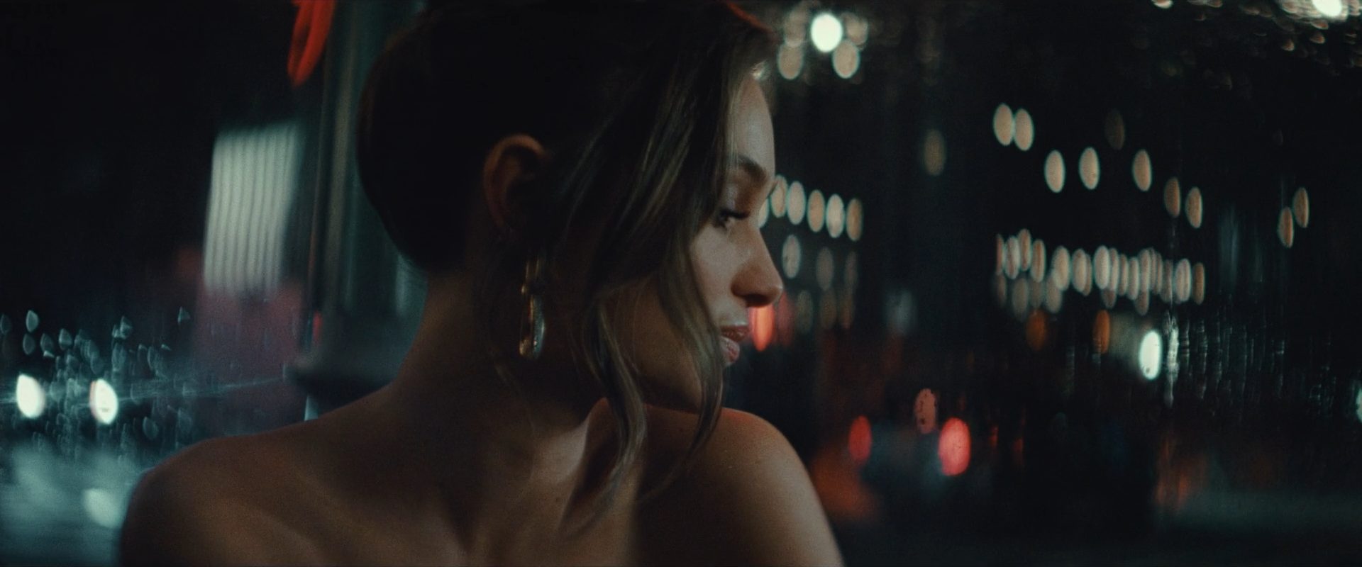 A woman in profile at night against city bokeh