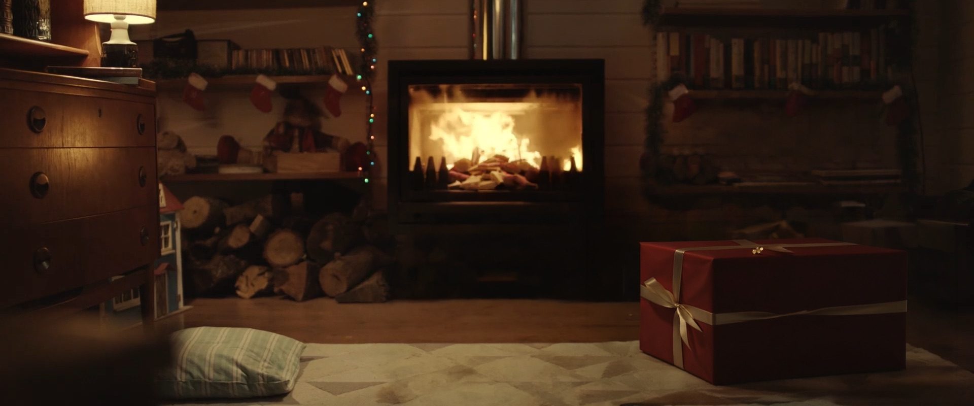 A lit fireplace with wrapped gifts in front of it